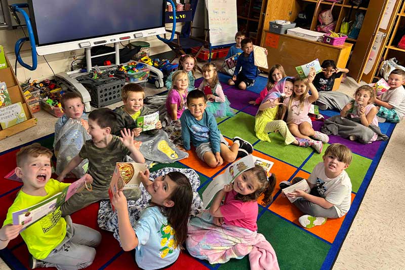Students smiling, sitting together on the floor.